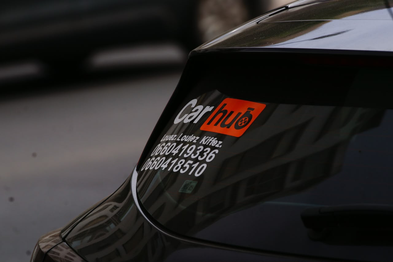 Rear window of a Carhub car showing the logo, the slogan and the agency’s two contact numbers
