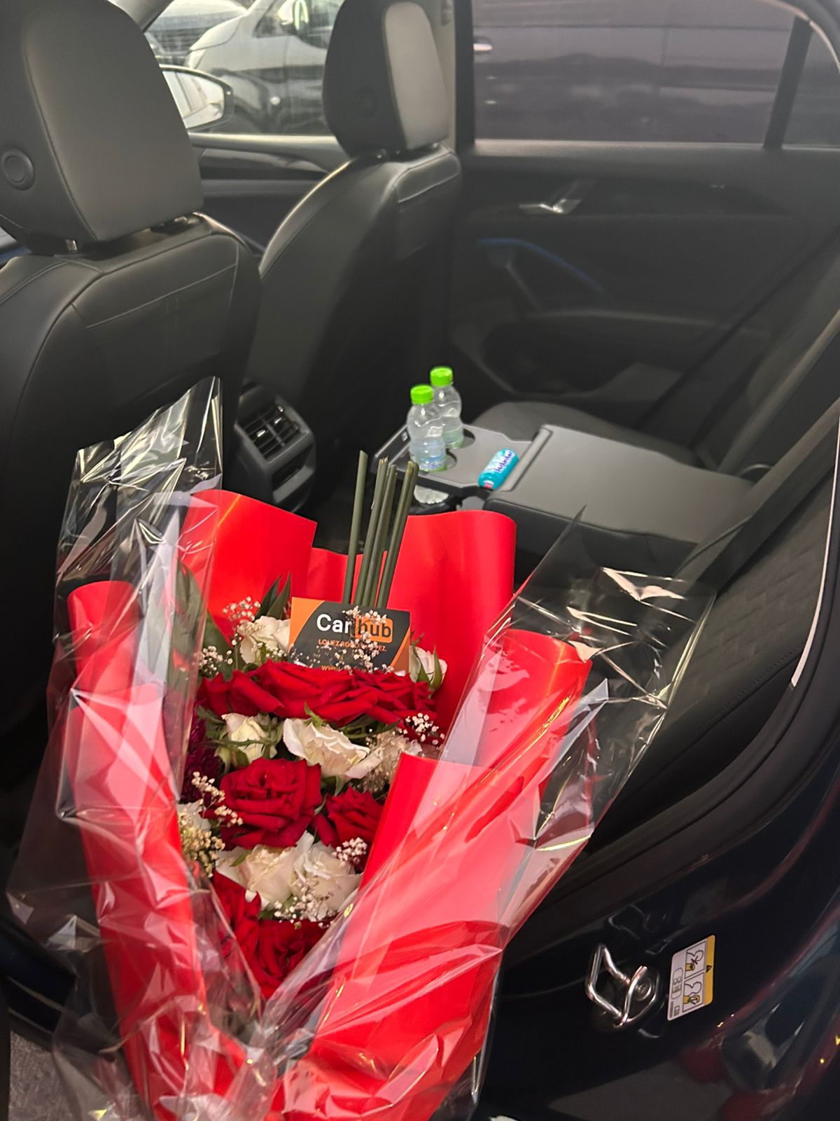 Bouquet of red and white roses with a Carhub card on the back seat of a rental car, with bottles of water prepared for the customer